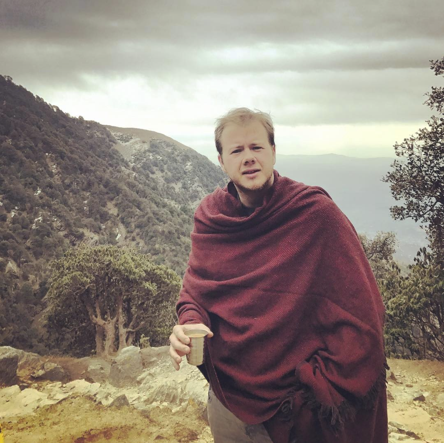 Yvo in the Indian Himalayas wrapped in a shawl, holding chai